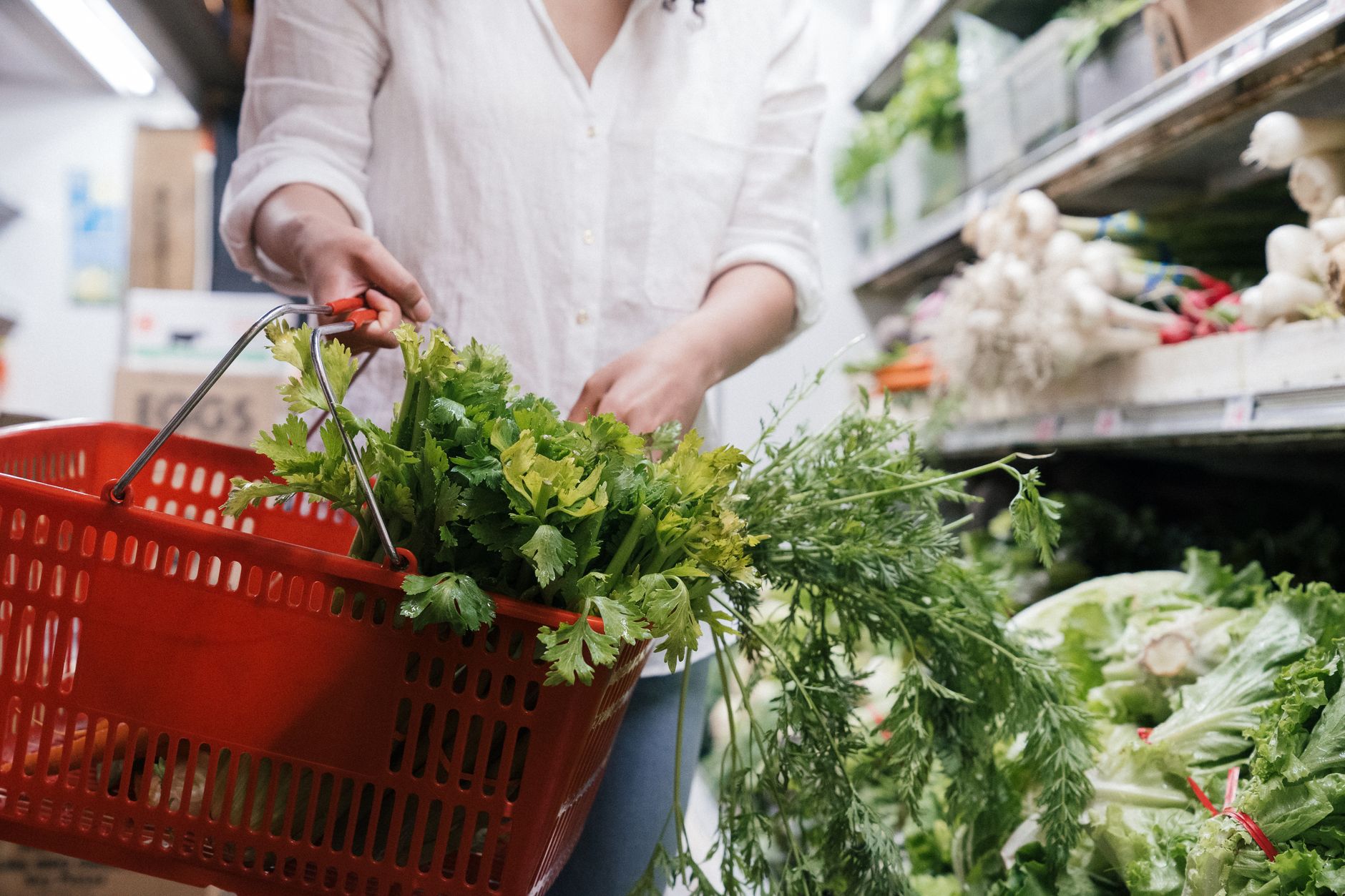 A shopping basket of fresh greens in a supermarket aisle