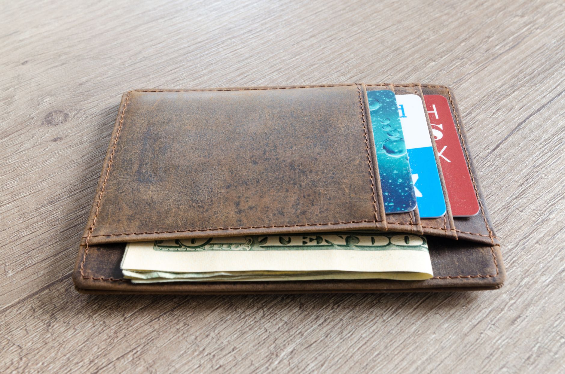 A credit card resting beside folded banknotes on a desk, illustrating a bank welcome cashback offer.