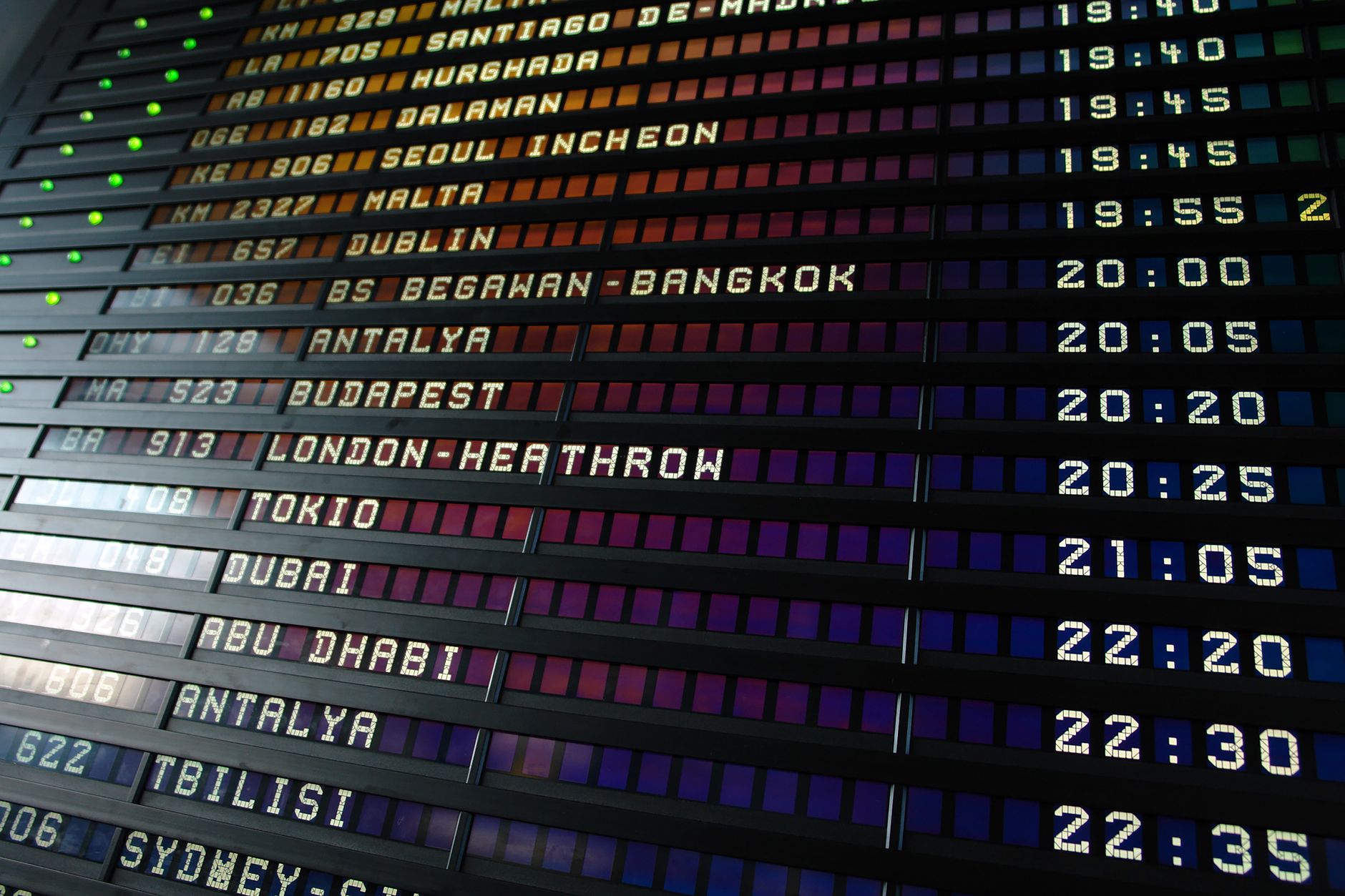 A split-flap airport departures board listing evening flights to cities including Seoul, Tokyo, Dubai and Sydney.