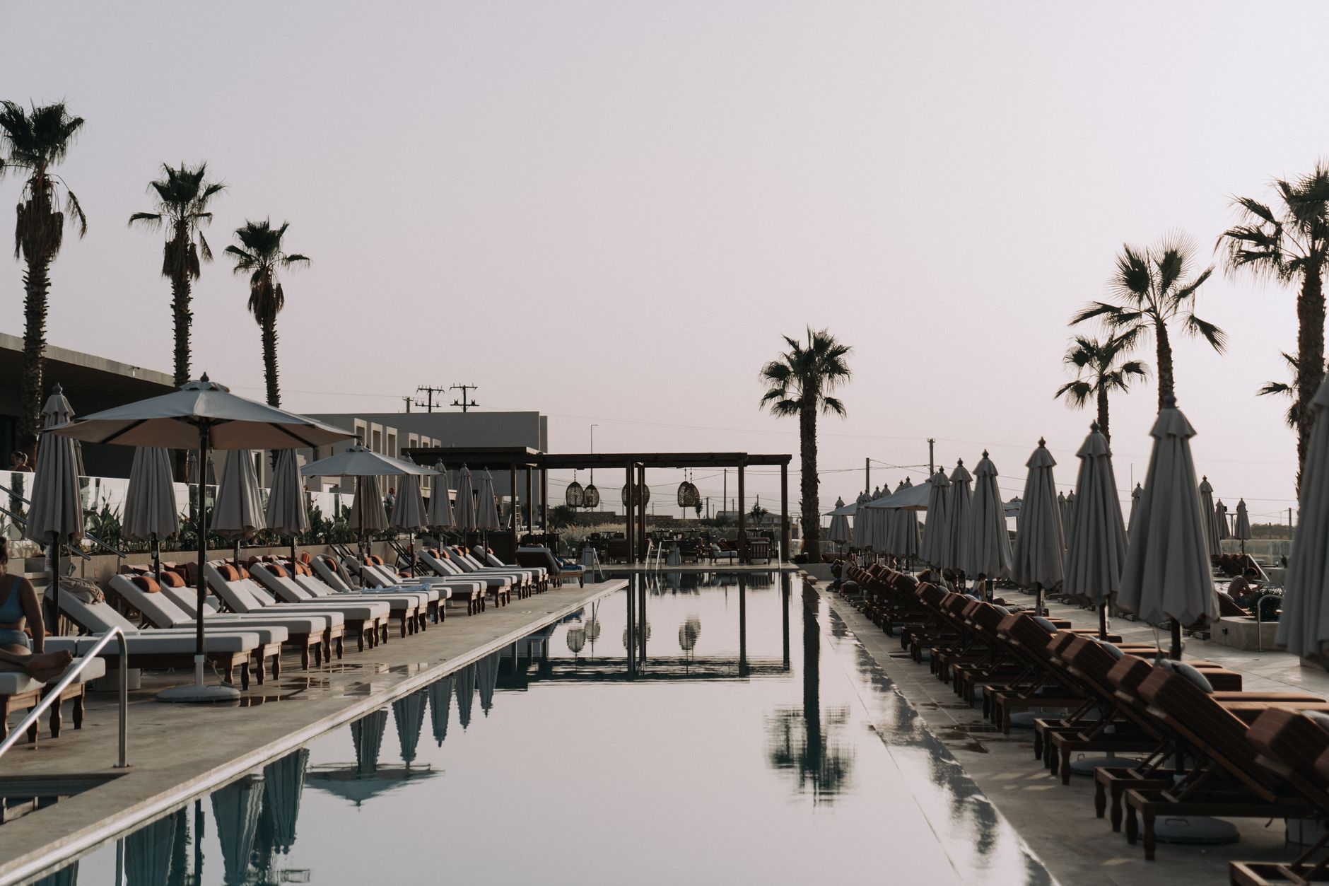 Rows of sun loungers and parasols along a palm-lined hotel pool