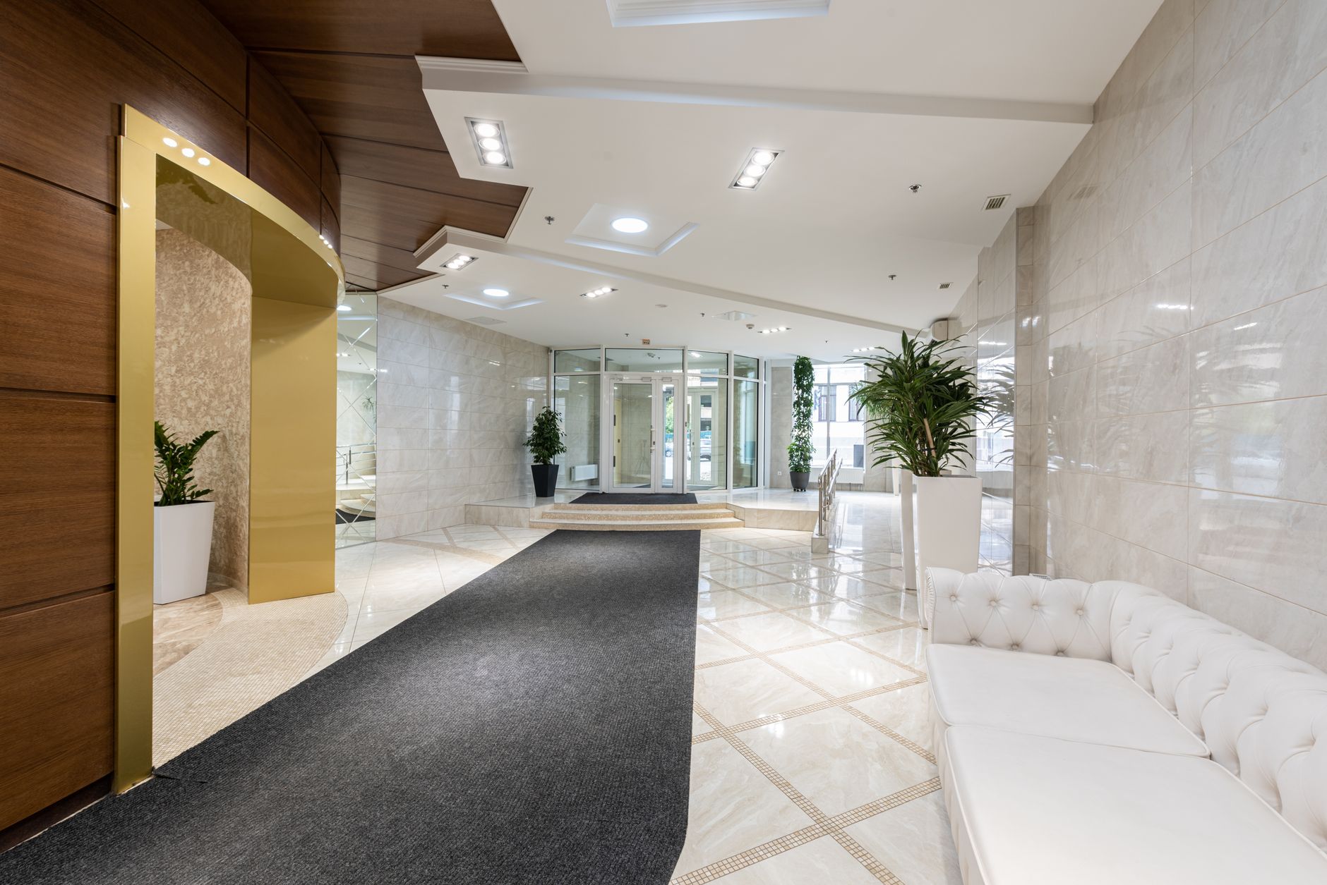 An empty modern hotel lobby with a marble reception desk in warm evening light